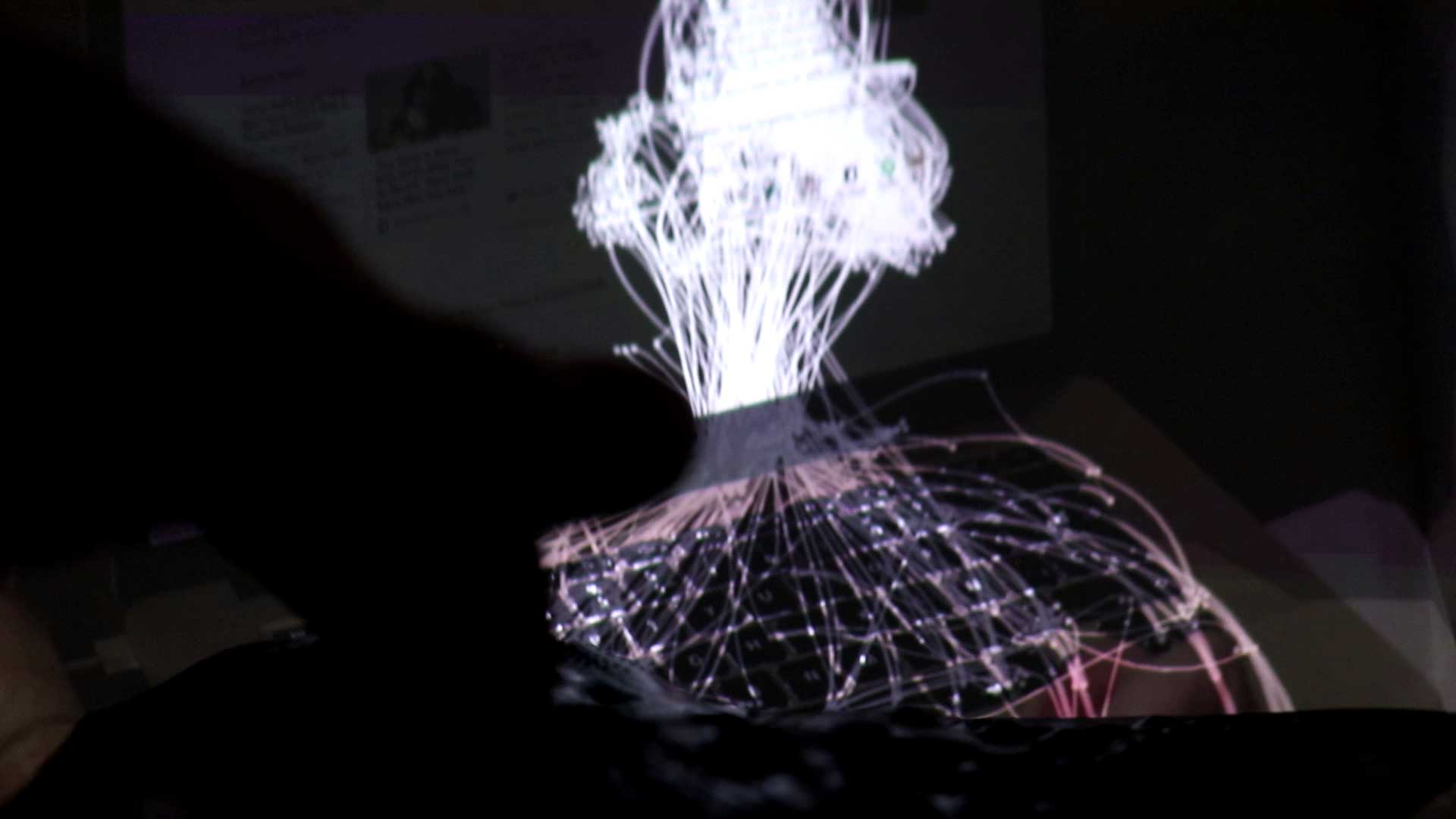 A composite image of a laptop, illuminated fibre optic cables, and a hand touching a surface.
