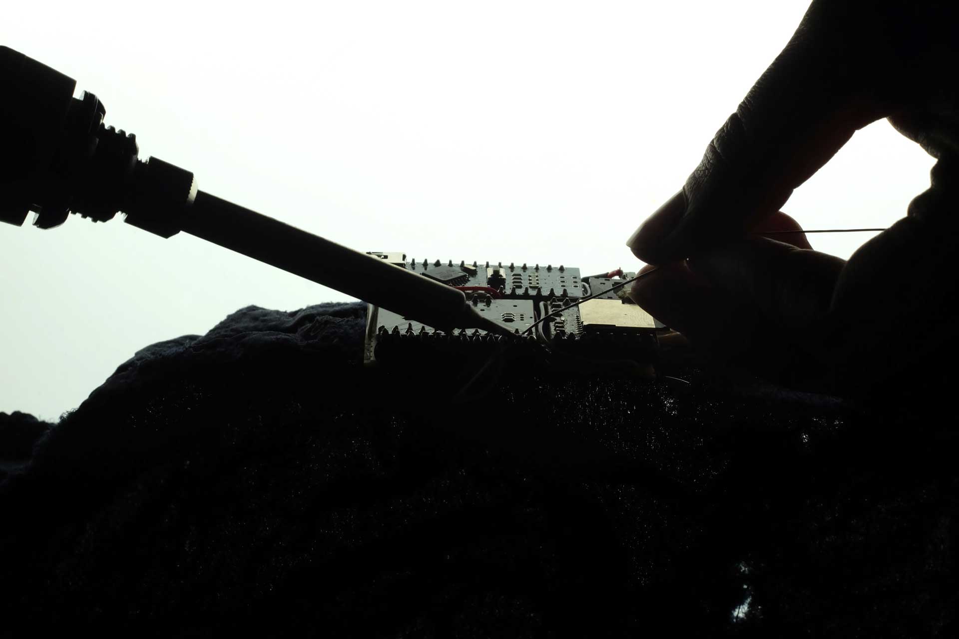 Hands soldering a circuit board.
